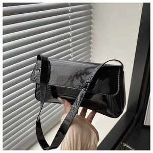 Gros plan du sac baguette en cuir verni noir avec finition brillante et rabat