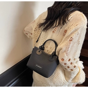 Detail view of the black woven texture and leather fashion label on this bucket bag