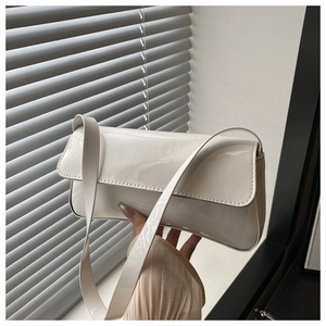 Détail d'un sac baguette en cuir verni blanc avec un rabat élégant et une finition brillante