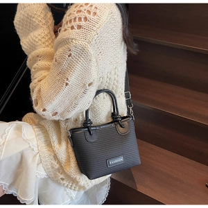 Close-up of black woven bucket bag with fashion label and adjustable shoulder strap