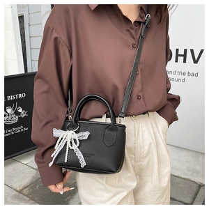 Litchi texture black mini bag with lace and pearl bow detail on a fashion model