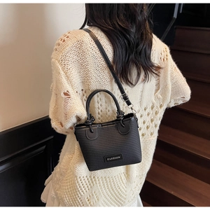 Detailed back view of a black woven bucket bag with fashion tag on casual outfit
