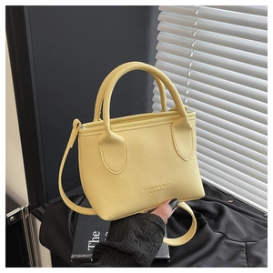 Detail of yellow pebbled leather handbag featuring brand embossing and elegant texture