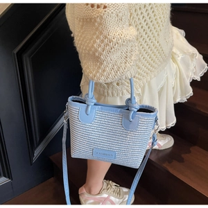 Close-up of blue and white woven bucket bag featuring knotted handles and leather strap