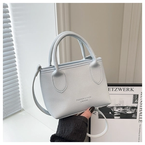 Close-up of light blue lychee pattern leather bucket bag with dual handles and strap
