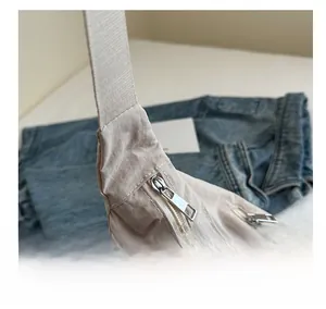 Detail view of smooth silver metal zippers and pleated nylon fabric on a beige tote bag