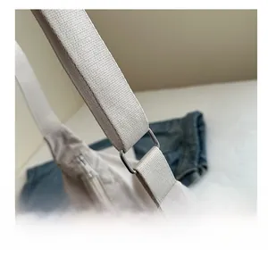 Detail of silver metal buckle and thick strap on beige nylon pleated tote bag