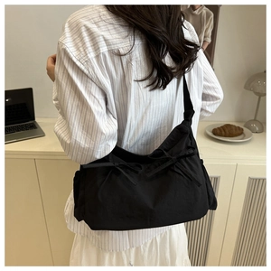 Détail du sac cabas plissé noir avec des nœuds décoratifs dans un cadre de vie décontracté