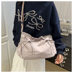 Détail du sac à bandoulière plissé lavande avec nœuds papillon et sangle réglable