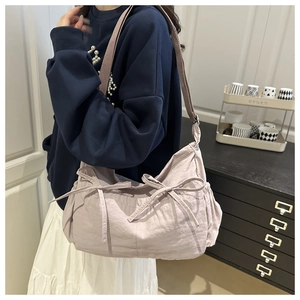 Detail of light purple pleated fabric tote with decorative bows and soft texture