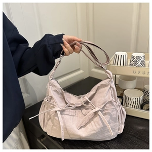 Détail d'un sac à bandoulière en nylon rose avec un design élégant à cordon et nœud