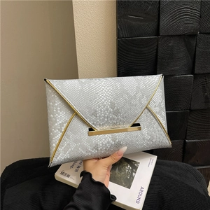 Pochette enveloppe argentée chic avec motif serpent et bordure dorée tenue à la main