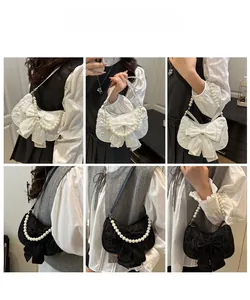 Detail view of bow shoulder bag showing pearl strap and 3D jacquard fabric texture