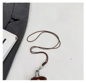 Detail of brown braided lanyard with silver metal swivel clasp on a leather mini pouch