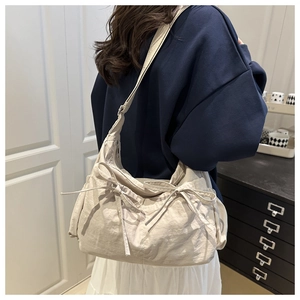 Gros plan du sac cabas en nylon plissé beige avec des détails de nœuds papillon