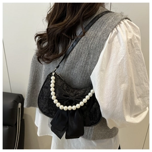 Detail of black lace shoulder bag with large satin bow and oversized pearl handle