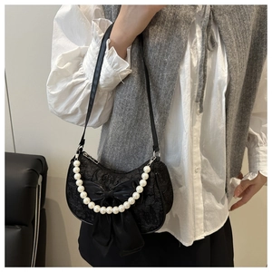 Vue détaillée du sac hobo noir avec nœud en soie et chaîne en perles sur mannequin