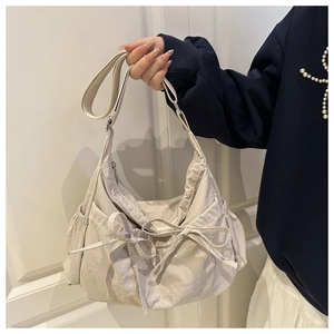 Détail du sac cabas en nylon froissé beige avec double nœud décoratif et poches latérales