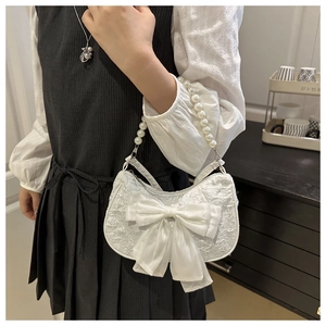 Gros plan du sac en jacquard blanc avec grand nœud en soie et poignée en perles