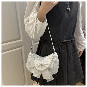 Detail of white lace handbag featuring a large organza bow and pearl handle ornament