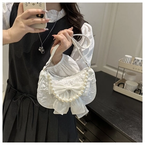 Détail du sac croissant blanc avec texture dentelle, nœud satin et chaîne perle