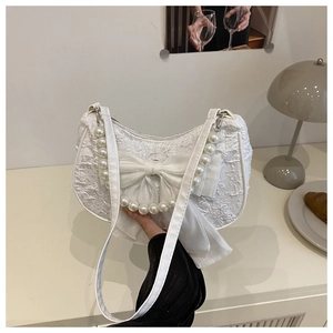 Détail du sac demi-lune blanc avec tissu jacquard texturé et décoration nœud en perles