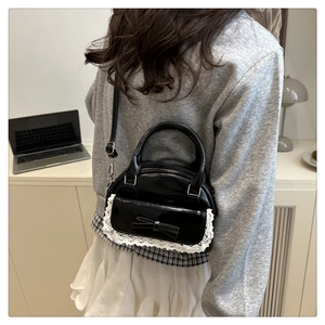 Détail du sac coquillage noir avec bordure en dentelle blanche et nœud 3D décoratif