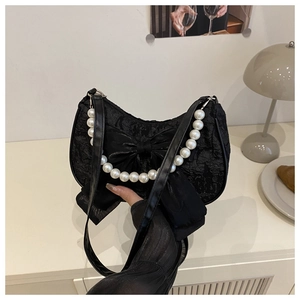 Gros plan du sac croissant noir avec grand nœud et poignée élégante en perles