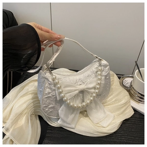 Gros plan d'un sac jacquard blanc avec grand nœud en soie et chaîne de perles décorative
