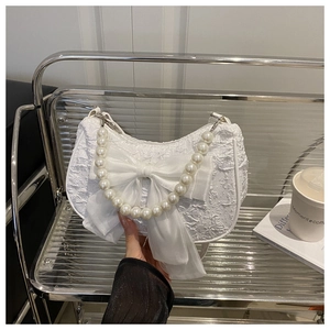 Détail du sac demi-lune blanc avec nœud en organza et bandoulière en perles blanches