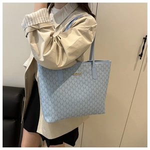 Détail du sac cabas bleu clair avec motif M et logo doré en gros plan soigné