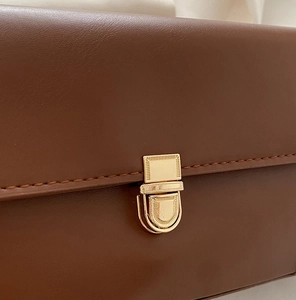Detailed view of the dark brown leather bag with a premium golden flip metal clasp lock