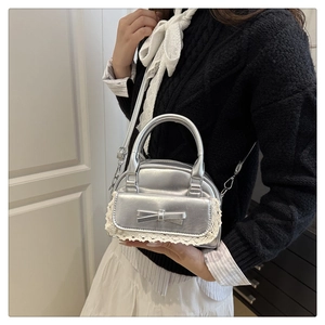 Borsa a mano argento con fiocco e pizzo bianco indossata a tracolla da una modella