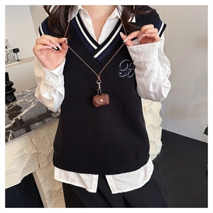 Mini brown leather bag necklace worn by a model in a preppy style knit vest
