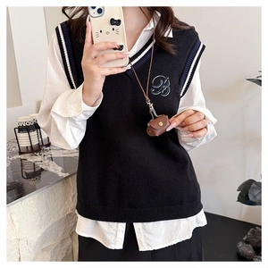 Detail of V-neck knit vest with letter B embroidery and blue-white striped trim details
