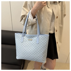 Détail du sac cabas bleu clair avec motif monogramme et plaque de logo dorée
