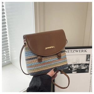 Close-up of a colorful woven crossbody bag with brown leather flap and golden logo