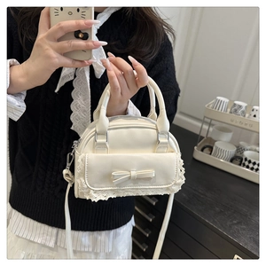 Detail einer beigen PU-Leder-Bowlingtasche mit eleganten Spitzenkanten und süßer Schleife