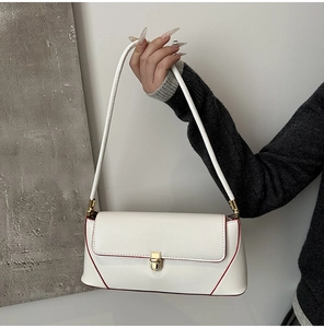 Detail of white baguette bag with red edges and golden metal clasp for women