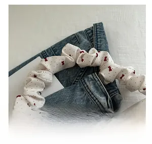 Detail of white pleated handle with red bow patterns and polka dots on a satin fabric bag