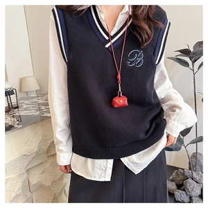 Detail of navy knit vest with V-neck stripes and embroidered B logo on chest pocket