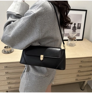 Detail of minimalist black faux leather underarm bag with elegant gold metal buckle