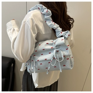 Detail of light blue shoulder bag featuring red bow prints and ruffled scrunchie strap