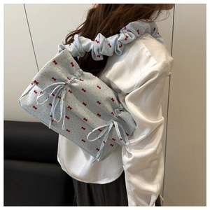 Detail of light blue pleated shoulder bag with red bow pattern on model side view