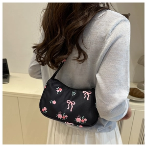 Detail of black shoulder bag with pink rose and bow prints in a home setting