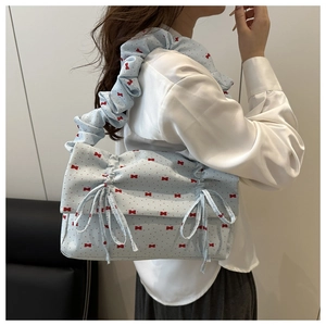 Detail of light blue ruffled shoulder bag with red bow prints and drawstring knots