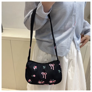 Detail of black crossbody bag with pink floral and bow prints worn on shoulder