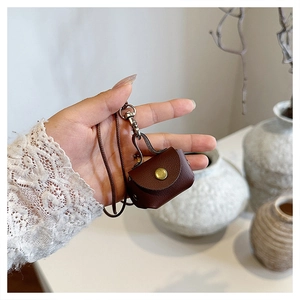 Gros plan d'une mini pochette en cuir marron avec bouton pression et cordon de cou