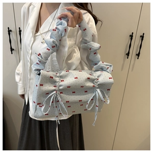 Detail of light blue cloud bag featuring red bow prints and ruffled drawstring texture