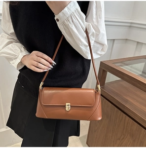 Close-up of caramel brown baguette bag with vintage gold swivel lock and smooth finish